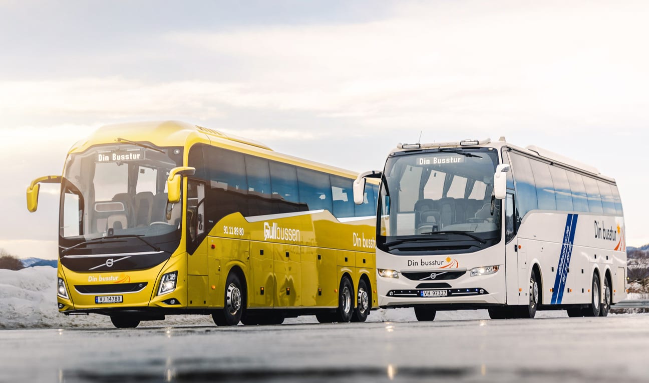 To turbusser fra Din Busstur, Gullbussen og en hvit turbuss, side om side på vinterføre