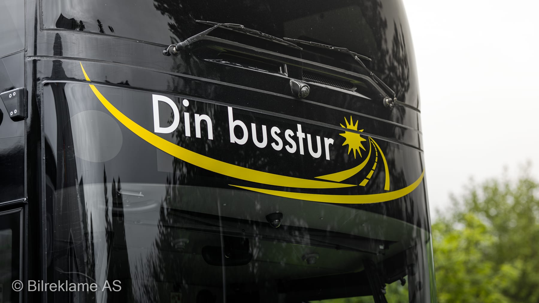 Din Busstur-logoen i gult på den svarte fronten av dobbeltdekkeren
