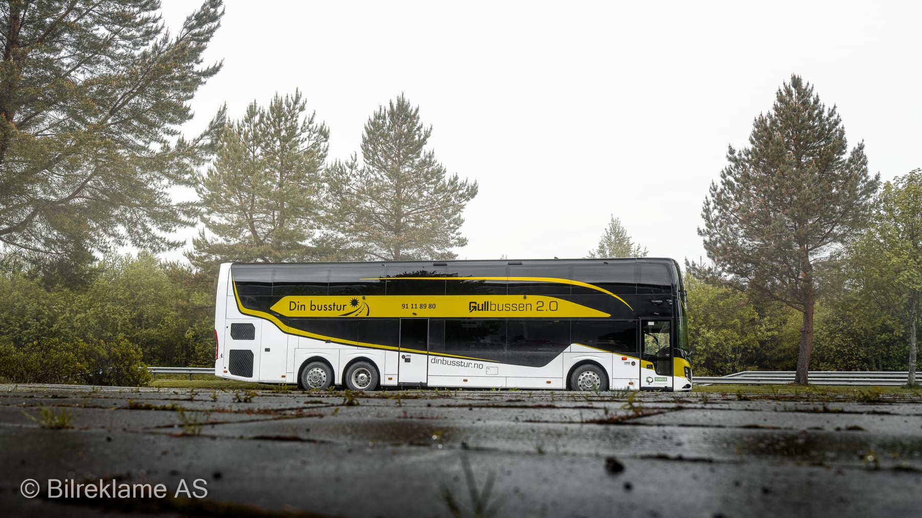 Gullbussen 2.0 fra siden – hvit Volvo 9900DD dobbeltdekker med svart og gul Din Busstur-dekor og navnet på lakken