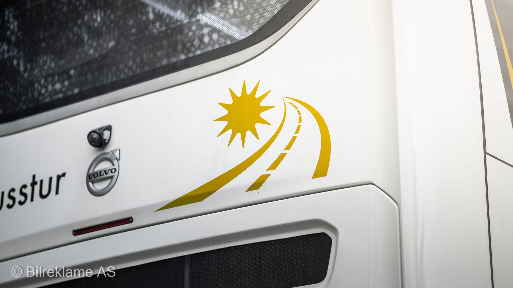 Sola og veien fra Din Busstur-logoen på hekken av dobbeltdekkeren